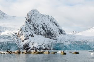 A snow covered mountain peak alongside a glacier in Svalbard.