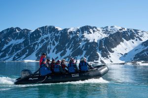 A zodiac full of passengers cruising in Arctic fjord.