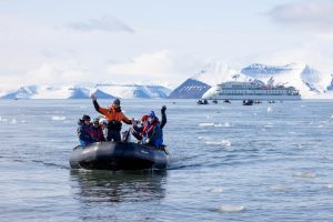 Zodiac cruising on the water with guests waving.