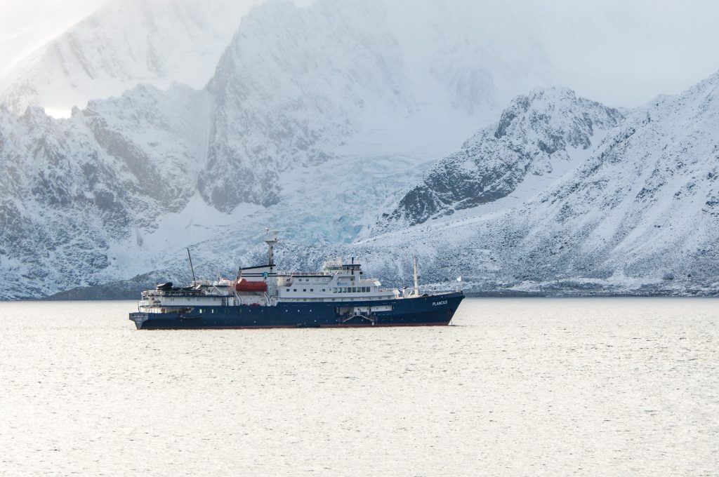 The ship Plancius with dramatic snow covered mountains in background.