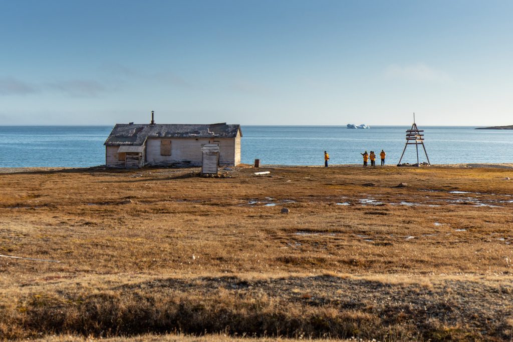 Guests standing near historic hut in Canadian Arctic.