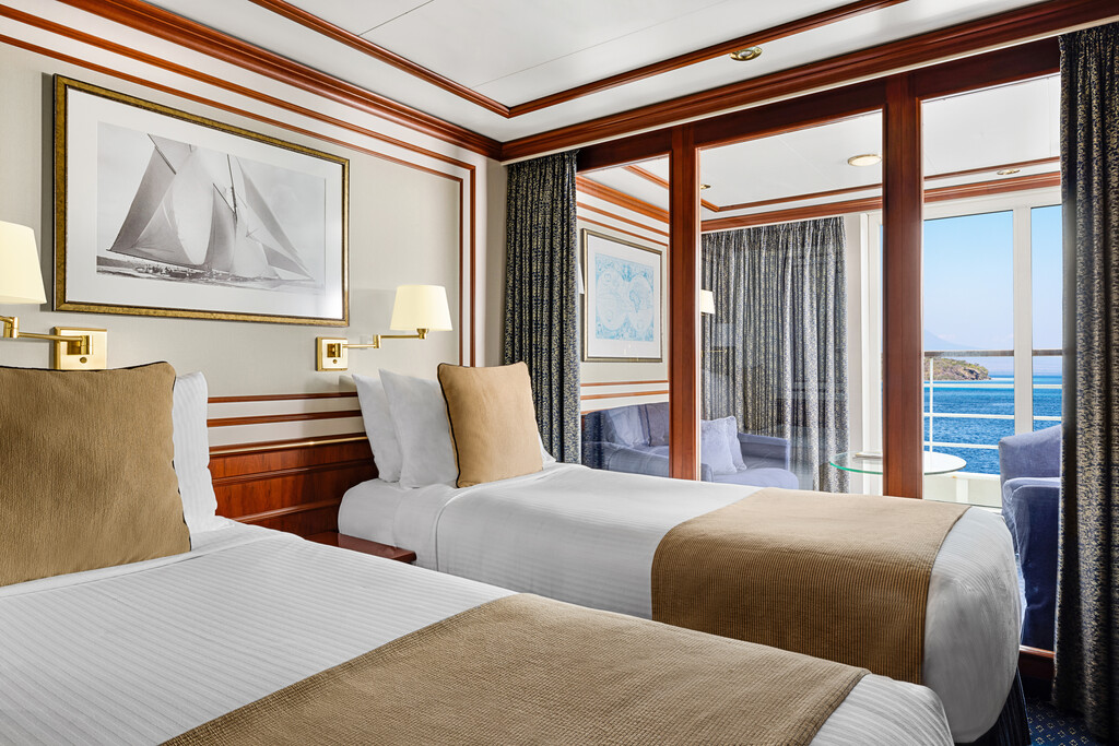 Two single beds with glass wall separating a sitting area with sofa.