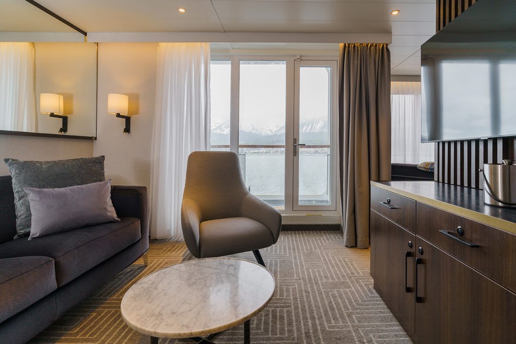 Sitting area in Owner's Suite on Ultramarine with couch, chair and floor to ceiling window leading to balcony.