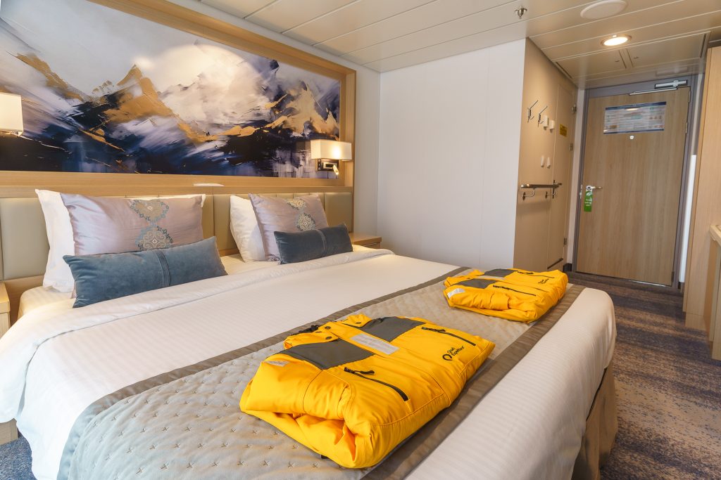 Double bed with 2 yellow parkas and entrance door in cabin on Ocean Explorer.