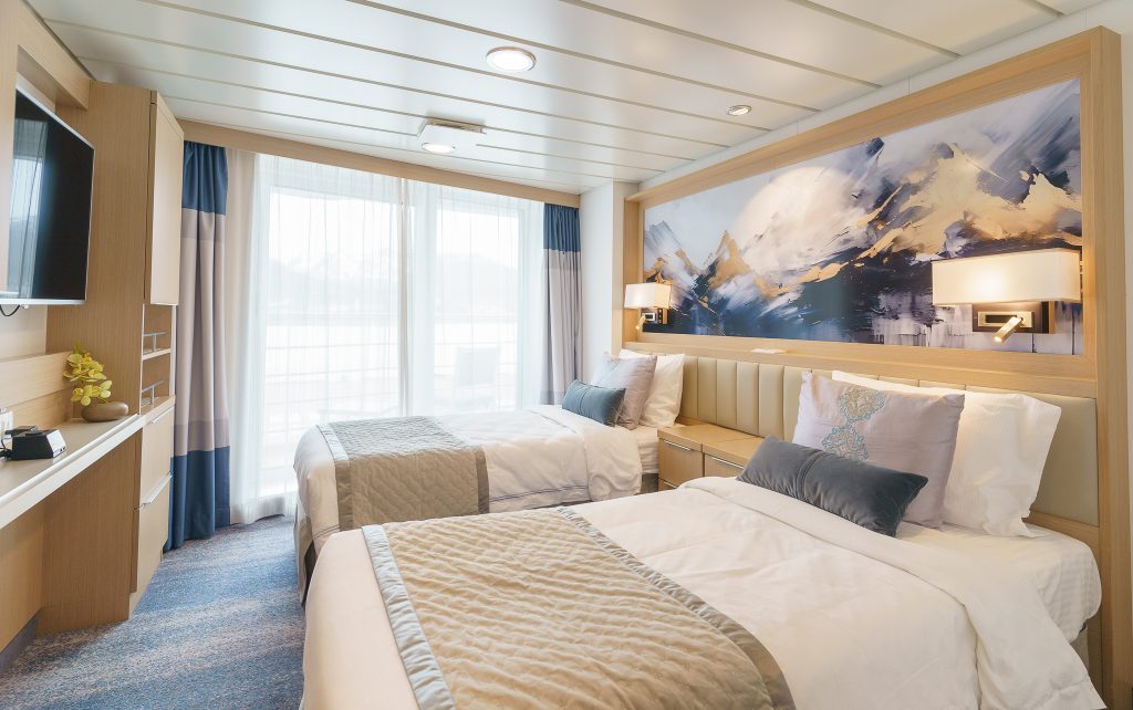 Deluxe Veranda Forward cabin on Ocean Explorer showing 2 twin beds TV, and floor to ceiling windows.