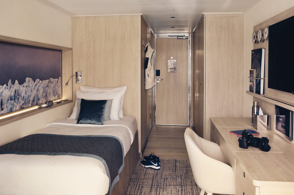 Single bed against wall and desk with chair.