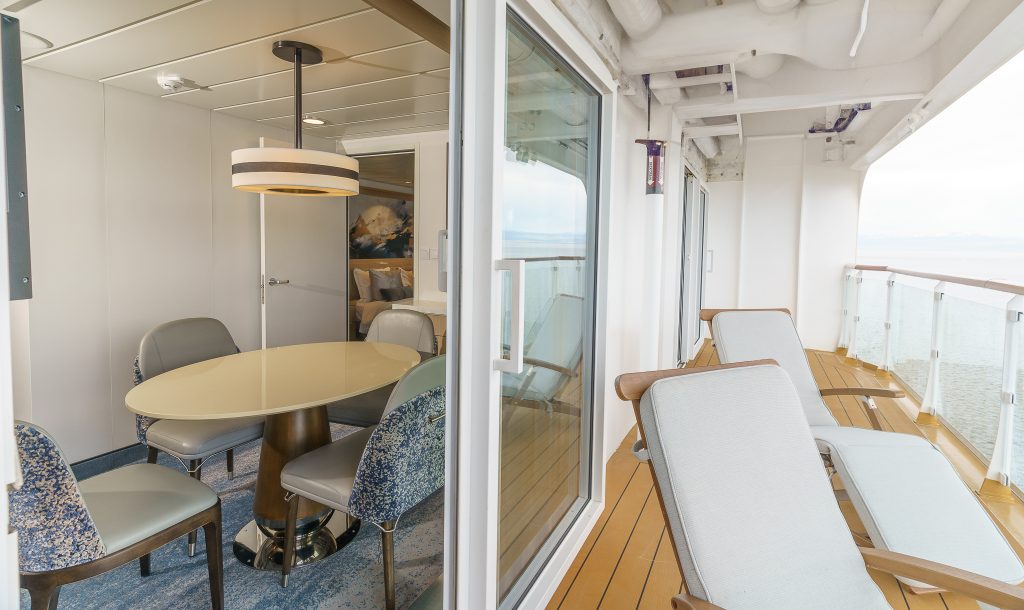View of private balcony and sitting area with small circular table in owner's suite on Ocean Explorer.