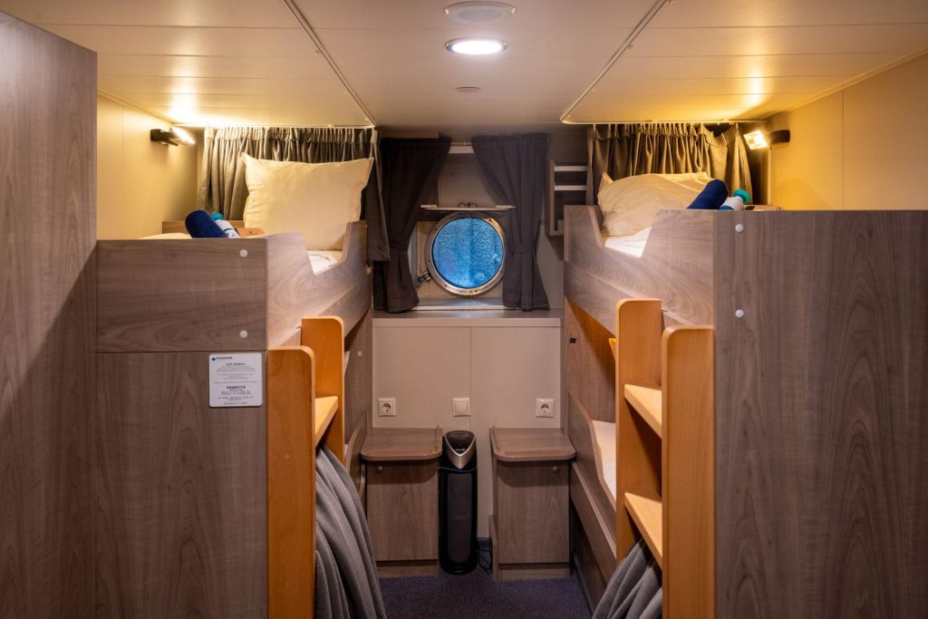 Quad porthole cabin on the Plancius with 2 sets of bunk beds and porthole window.