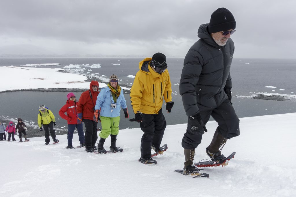 Line of people snowshoeing up hillside in Antarctica.