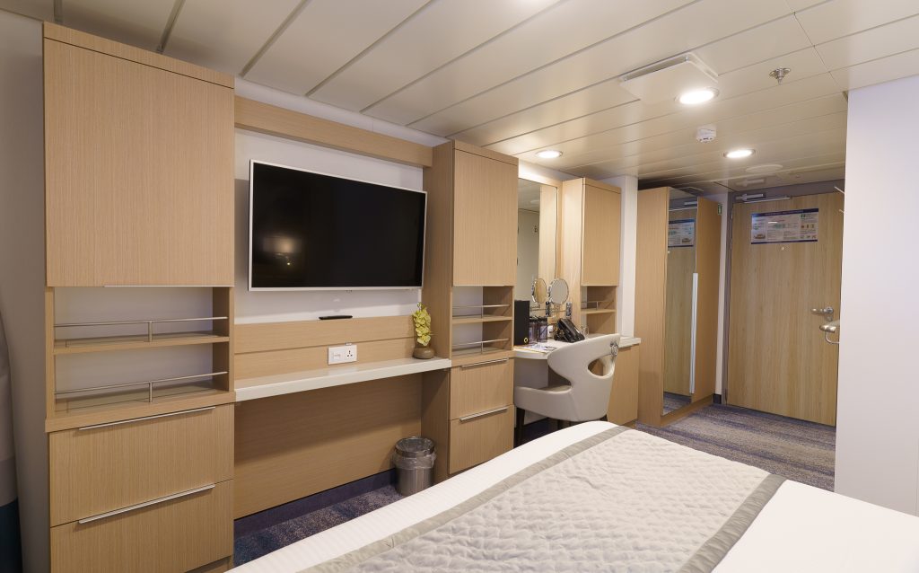 TV on the wall, desk with chair and double bed.