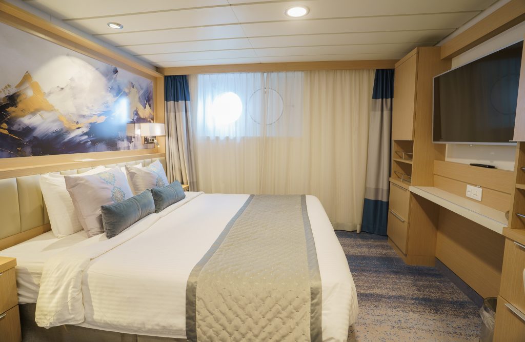 Studio Single interior with double bed, TV and porthole on Ocean Explorer.