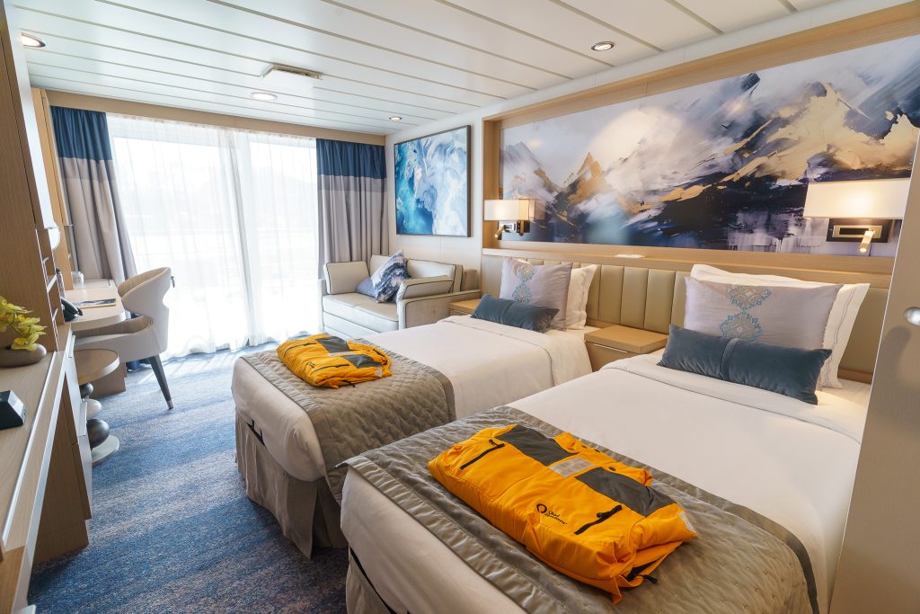 Veranda Suite on Ocean Explorer with 2 twin beds, chair and floor to ceiling window.