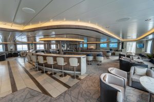 Greg Mortimer lecture lounge with rows of barstools, chairs, tables, flat screen TV's and large windows.