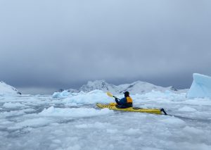 A lone kayaker paddling through the ice in Antarctica.