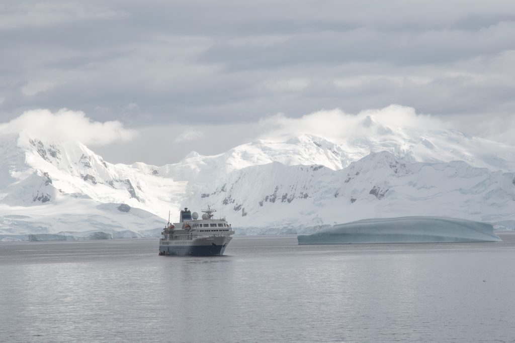 The ship Seaventure in Antarctica with snow covered mountains in background.