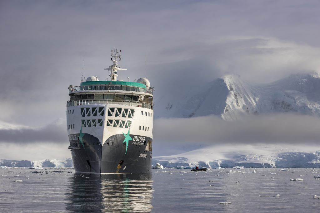 The ship Sylvia Earle on the water with snow covered mountains in background. 