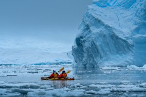 Kayakers next to large Antarctic iceberg.
