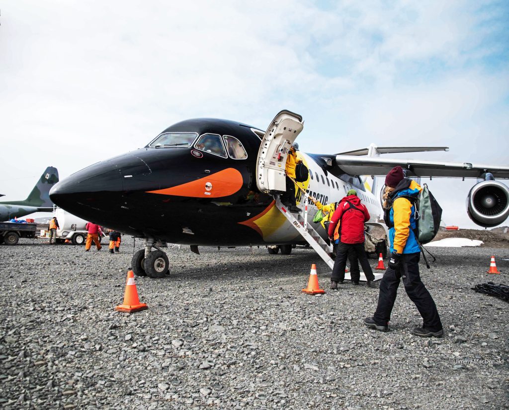Passengers boarding an airplane on rocky runway. 