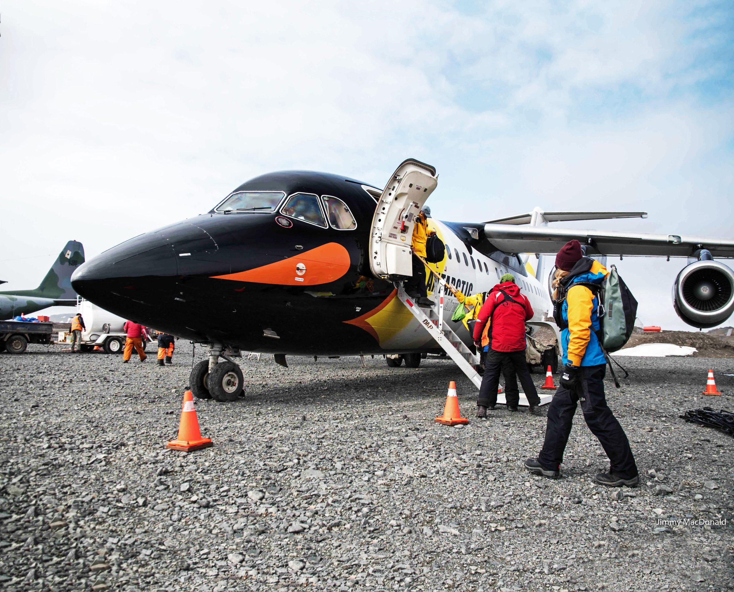 Passengers boarding an airplane on rocky runway.