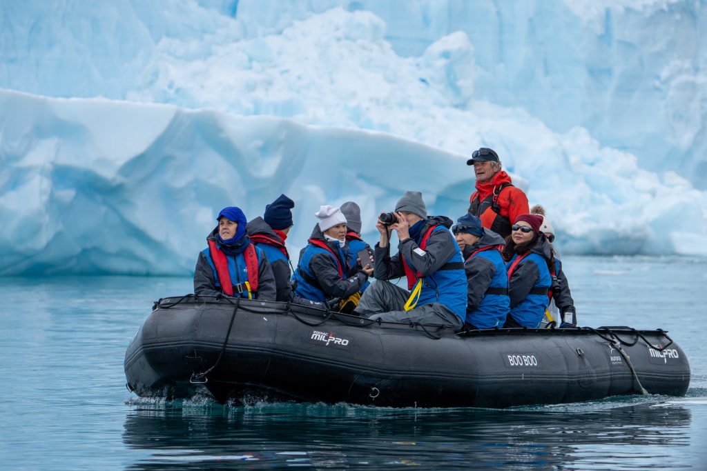 Guests on a zodiac with glacier in background in Antarctica