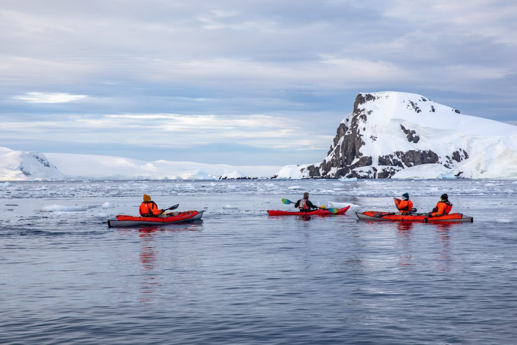 Guests kayaking with snow covered mountain in background.