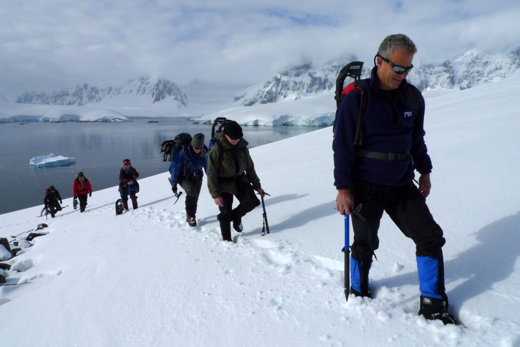 Guests hiking up snowy hillside in Antarctica.