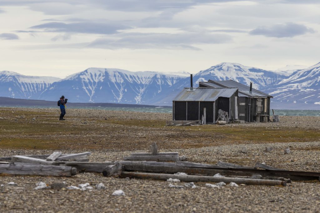 Guest on shore in Svalbard standing near trapping hut.