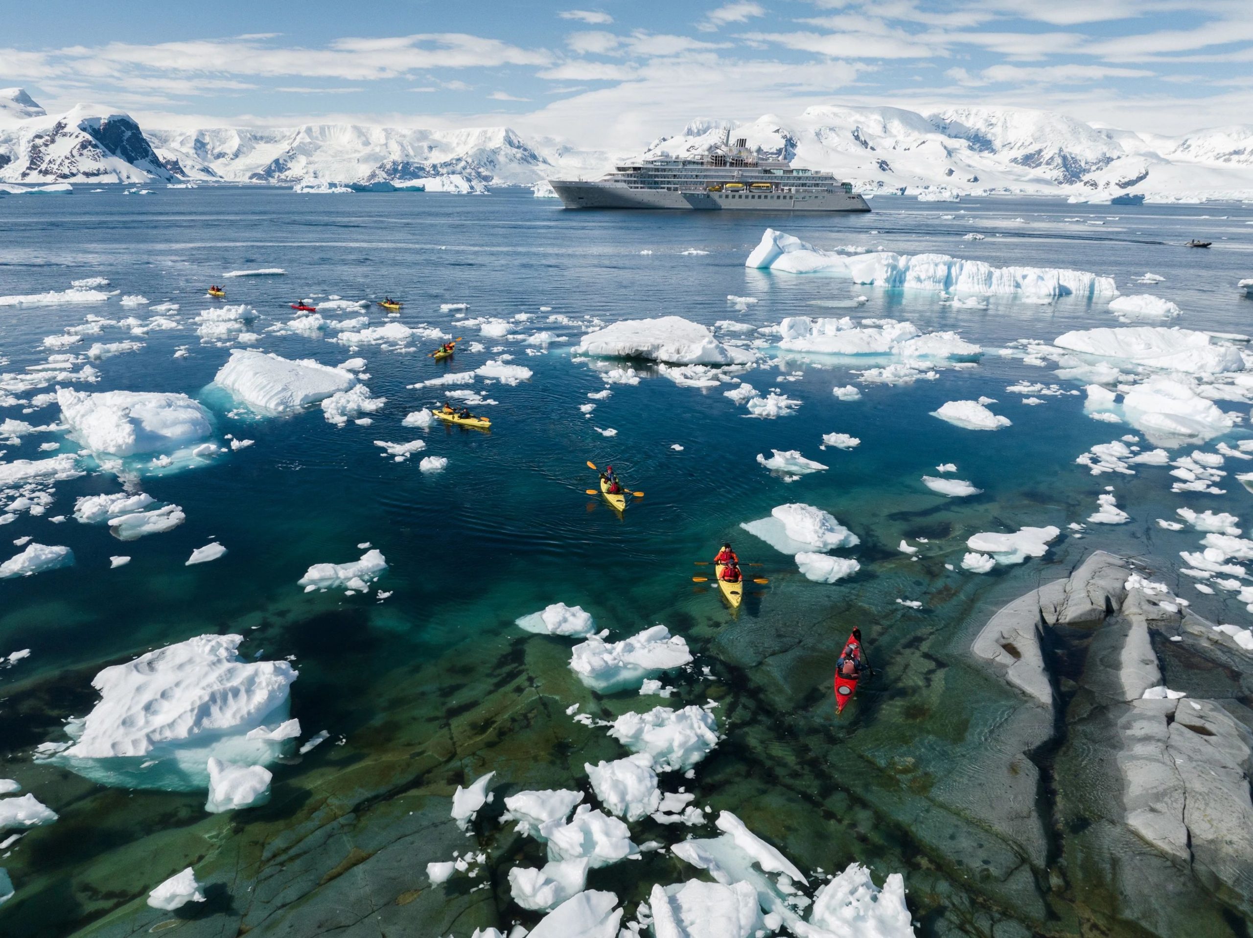 Kayakers in Antarctica with ship in background.