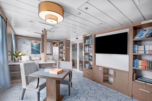 Ocean Victory library with table, bookshelves and a flat screen TV.