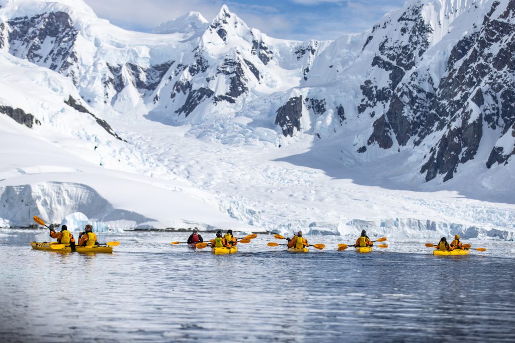 Kayakers on the water paddling toward mountains.
