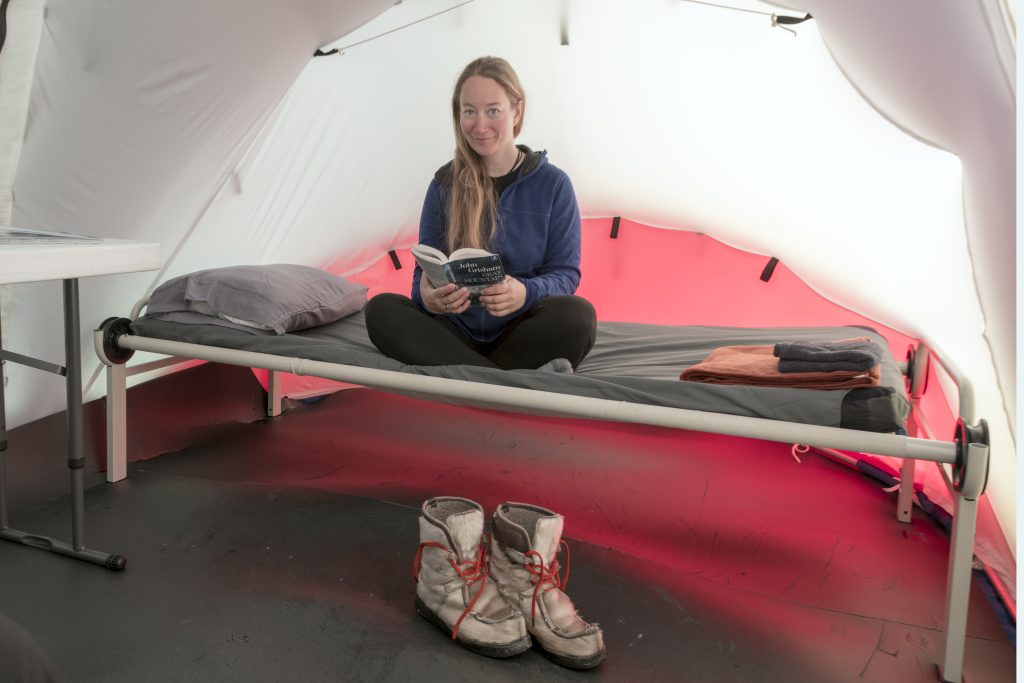 A woman reads a book inside a clam tent.