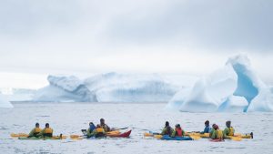 Kayakers on the water with icebergs in background.