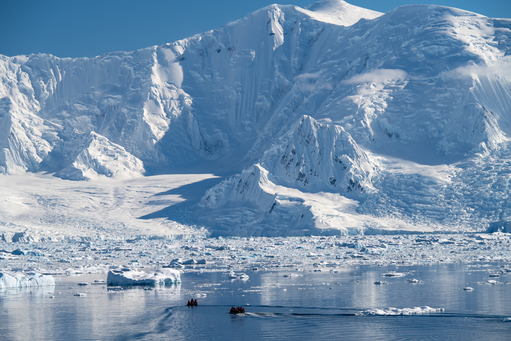 Ice landscape with zodiacs on the water.